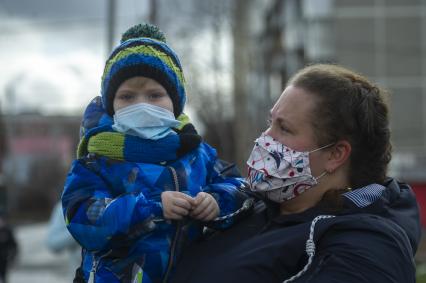 Екатеринбург. Женщина с ребенком в медицинских масках набдюдают за проведением репетиции парада.