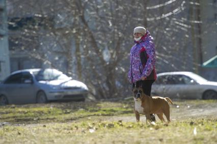 Екатеринбург. Женщина в медицинской маске гуляет с собакой породы \'американский стаффордширский терьер\' во время эпидемии коронавирусной инфекции COVID-19