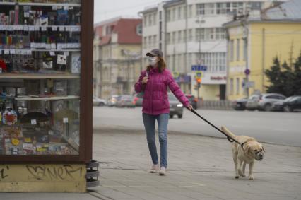 Екатеринбург. Девушка в медицинской маске гуляет с собакой в наморднике во время эпидемии коронавирусной инфекции COVID-19