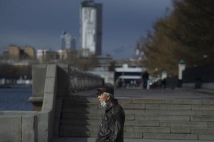 Екатеринбург.Пожилой мужчина в медицинской маске на опустевшей набережной городского пруда во время эпидемии коронавирусной инфекции COVID-19