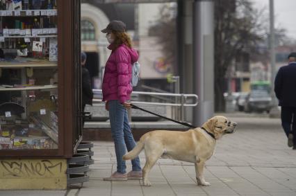 Екатеринбург. Девушка в медицинской маске гуляет с собакой в наморднике во время эпидемии коронавирусной инфекции COVID-19