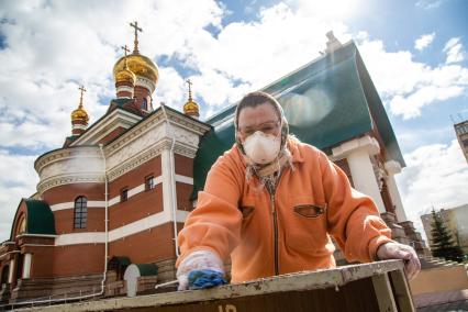 Челябинск. Женщина в медицинской маске проводит дезинфекцию перед началом  церковной службы.