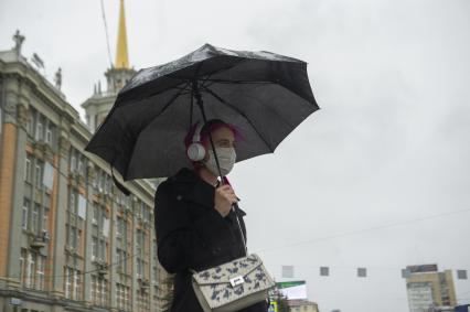 Екатеринбург. Девушка в медицинской маске по зонтом во время режима самоизоляции введенного для нераспространения коронавирусной инфекции COVID-19