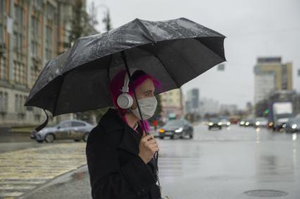 Екатеринбург. Девушка в медицинской маске по зонтом во время режима самоизоляции введенного для нераспространения коронавирусной инфекции COVID-19