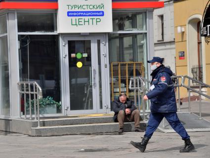 Москва. Мужчина сидит на ступенях у  туристического центра.