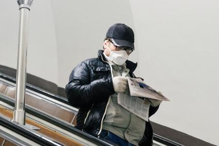 Санкт-Петербурга.    Мужчина в медицинской маске на эскалаторе в метро.