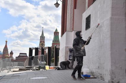 Москва. Рабочий в медицинской маске красит стену дома.