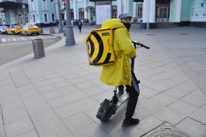 Москва. Сотрудник сервиса доставки еды в медицинской маске.