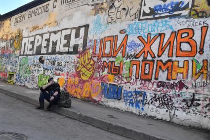 Москва. Молодой человек сидит у стены Цоя на Старом Арбате.