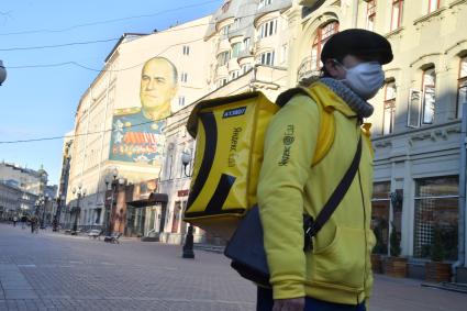 Москва. Сотрудник сервиса доставки еды в медицинской маске.