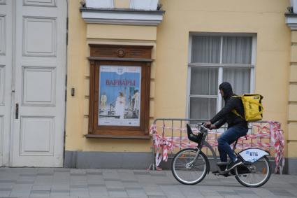 Москва. Сотрудник сервиса доставки еды на пустынной улице.