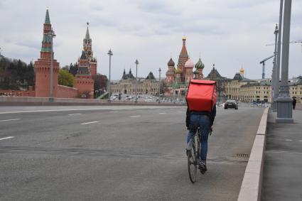 Москва.  Сотрудник сервиса доставки еды на Большом Москворецком мосту.