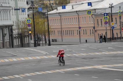 Москва. Сотрудник сервиса доставки еды на пустынной улице.