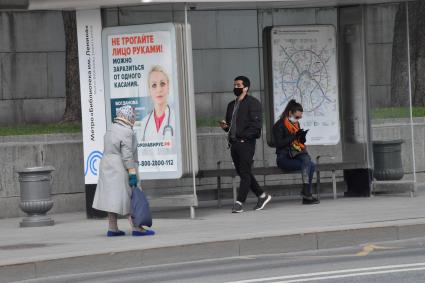 Москва. Прохожие в медицинских масках на остановке общественного транспорта.