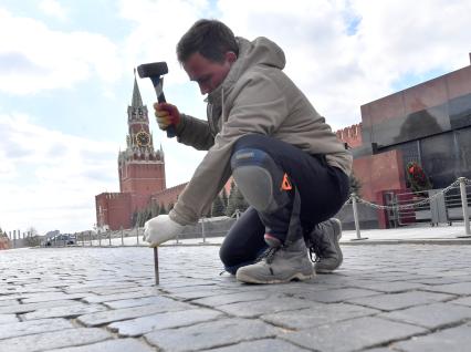 Москва. Рабочий ремонтирует брусчатку на Красной площади.