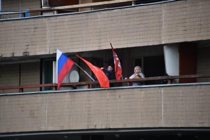 Москва. Мужчины и женщина на балконе с флагами.