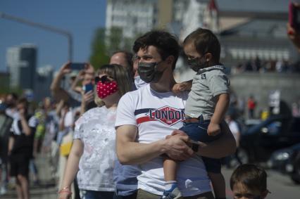 Екатеринбург. Горожане наблюдают за прохождением колонны военных грузовиков с платформами-баннерами с изображением основных этапов Великой Отечественной войны, на проспекте Ленина во время праздничных мероприятий в честь 75-й годовщины победы в ВОВ, во время режима самоизоляции введеного для нераспространения новой коронавирусной инфекции COVID-19