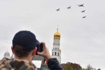 Москва.  Мужчина фотографирует во время воздушного парада Победы в Москве.