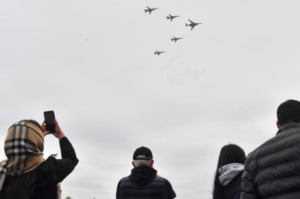 Москва.  Женщина фотографирует во время воздушного парада Победы в Москве.