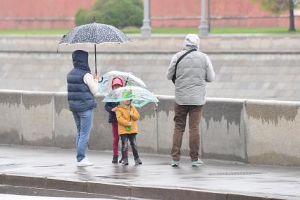 Москва.   Мужчина, женщина и дети под дождем.