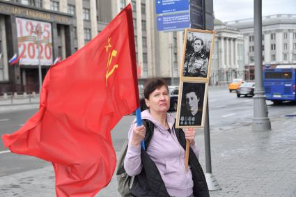 Москва.  Женщина с портретами своих родственников - участников Великой Отечественной войны  и красным  флагом  во время празднования дня Победы.