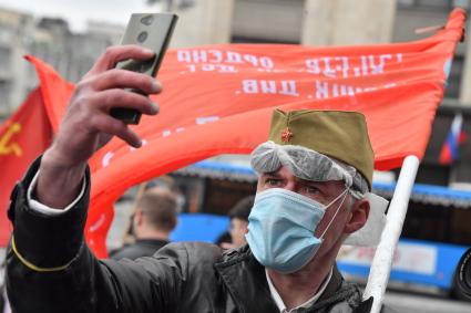 Москва. Мужчина с красным флагом делает селфи во время празднования дня Победы.
