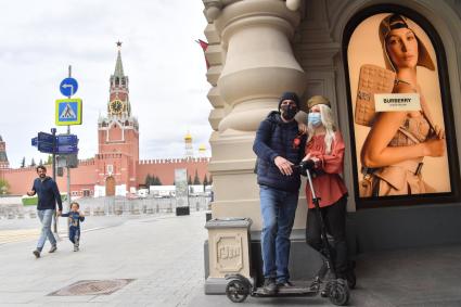 Москва.  Молодые люди в медицинских масках на Красной площади во время празднования Дня Победы.