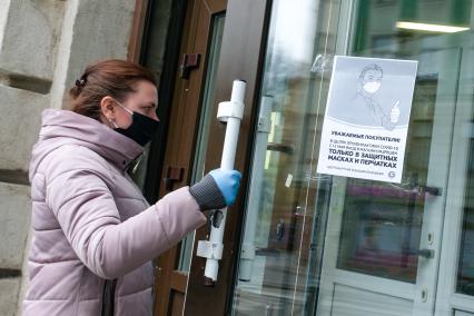 Санкт-Петербург. Женщина в медицинской маске и перчатках взодит в магазин.