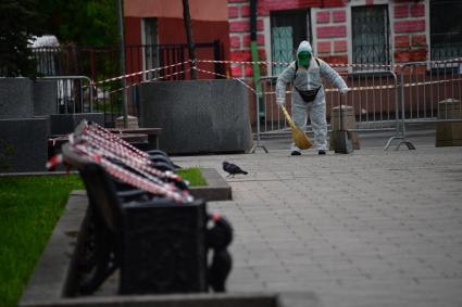 Москва. Дворник подметает двор в защитном костюме.