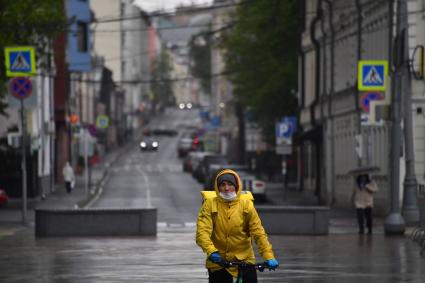 Москва. Сотрудник службы доставки еды в медицинской маске на улице города.