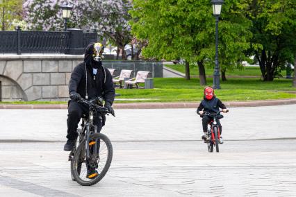 Москва. Мужчина с ребенком катается на велосипеде в Александровском саду.