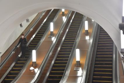 Москва. Женщина в медицинской маске одна на эскалаторе в метро.