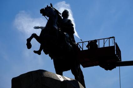 Санкт-Петербург. Сотрудник коммунальной службы моет памятник Петру I на Сенатской площади.