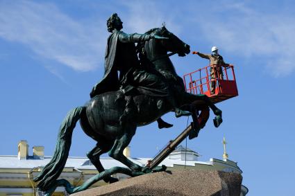 Санкт-Петербург. Сотрудник коммунальной службы моет памятник Петру I на Сенатской площади.