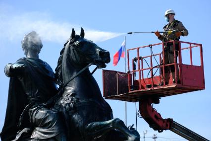 Санкт-Петербург. Сотрудник коммунальной службы моет памятник Петру I на Сенатской площади.