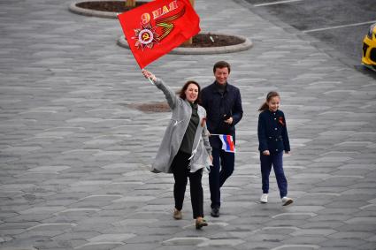 Москва. Прохожие с флагом  на Красной площади во время  воздушного парада Победы в Москве.