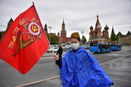 Москва. Девочка с флагом в медицинской маске и пилотке на Васильевском спуске  во время  воздушного парада Победы в Москве.