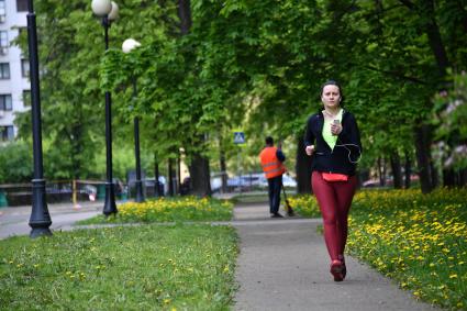 Москва. Женщина совершает пробежку на  территории парка.