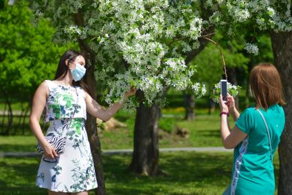Новосибирск. Девушка в медицинской маске около цветущего дерева.