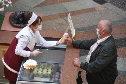 Москва. Мужчина в медицинской маке покупает мороженое в ГУМе , где возобновлена торговля в рамках очередного этапа отмены ограничений, введенных из-за коронавируса.