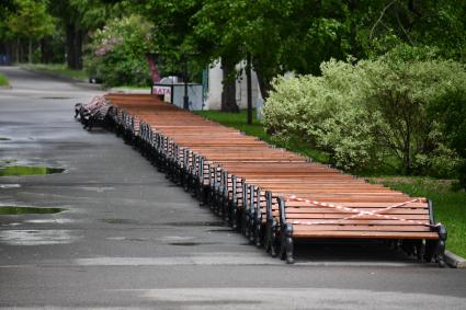 Москва.  Скамейки с ограничительной лентой на аллее Парка Горького.