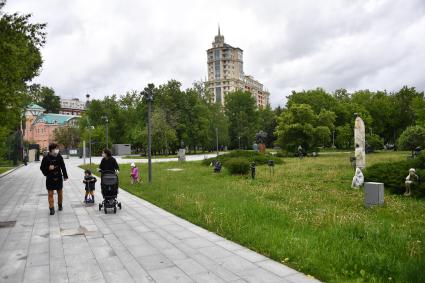 Москва.  Женщина и мужчина с детьми гуляют в парке Музеон.