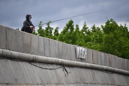 Москва.  Мужчина ловит рыбу на Крымской набережной.