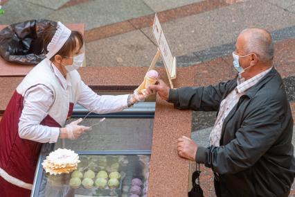 Москва. Мужчина в медицинской маке покупает мороженое в ГУМе , где возобновлена торговля в рамках очередного этапа отмены ограничений, введенных из-за коронавируса.