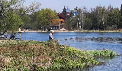 Московская область, деревня Вялки. Мужчина ловит рыбу на берегу озера.