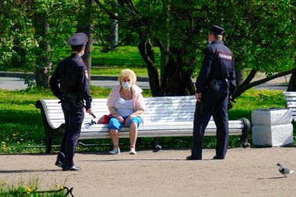 Санкт-Петербург.  Сотрудники полиции общаются с женщиной в парке.