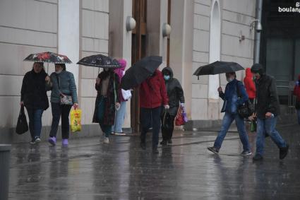 Москва.  Прохожие под дождем у метро Парк Культуры.