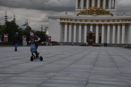 Москва.  Посетители катаются на самокатах на ВДНХ.