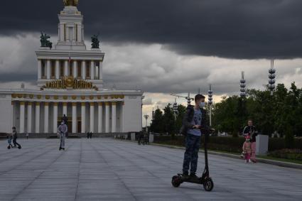 Москва.  Посетители катаются на самокатах на ВДНХ.