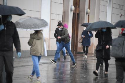 Москва.  Прохожие под дождем у метро Парк Культуры.